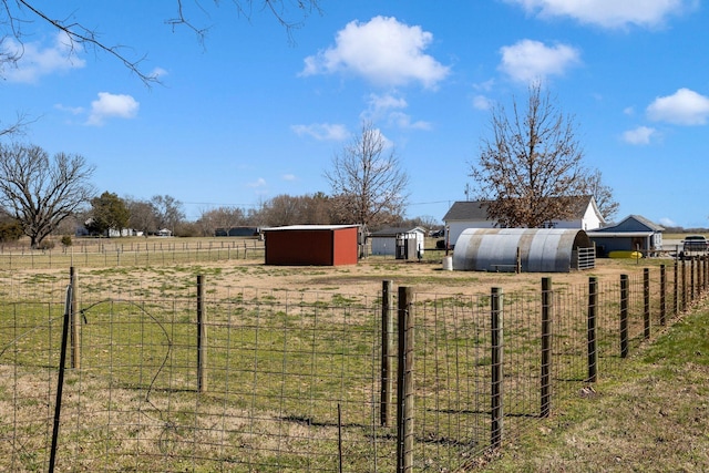 view of yard with an outbuilding, a rural view, an outdoor structure, and fence