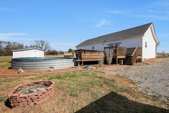 rear view of house featuring an outdoor pool, an outdoor structure, a fire pit, crawl space, and a deck