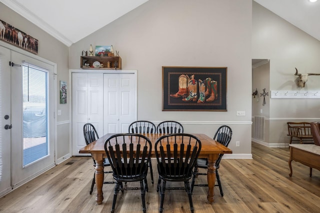 dining room featuring high vaulted ceiling, visible vents, baseboards, and light wood-style floors