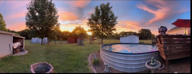 yard at dusk with a storage shed, an outbuilding, and fence