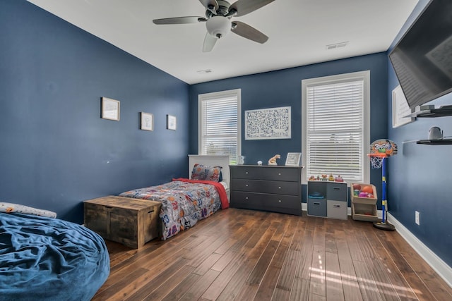 bedroom with ceiling fan, visible vents, baseboards, and wood finished floors