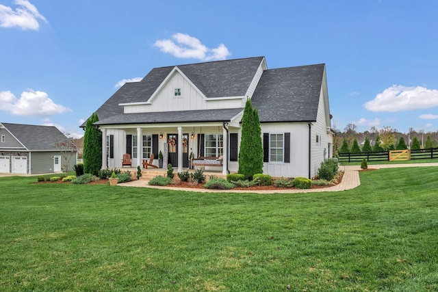 modern farmhouse featuring covered porch, board and batten siding, a front yard, and fence