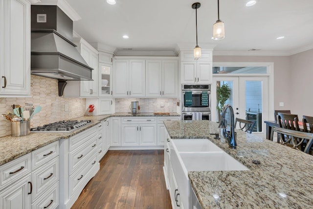 kitchen featuring ornamental molding, a sink, stainless steel appliances, white cabinets, and custom exhaust hood