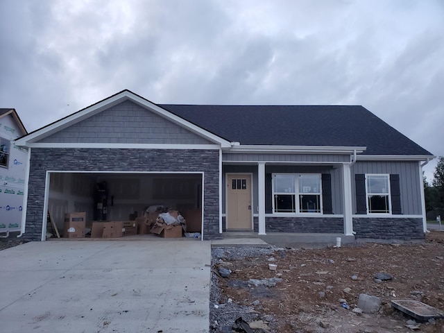 view of front of house featuring concrete driveway, a garage, board and batten siding, and stone siding