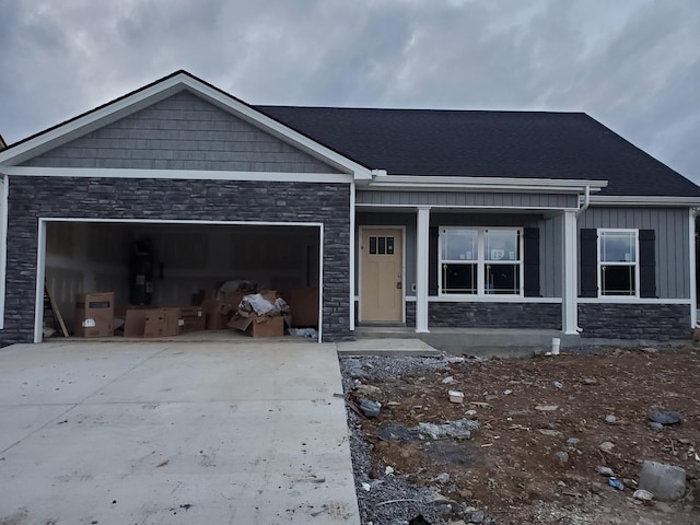 view of front of house featuring stone siding, a garage, board and batten siding, and driveway