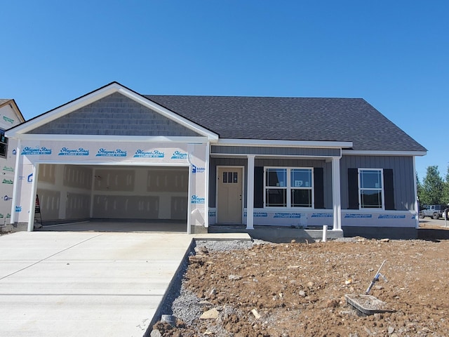 unfinished property featuring a garage, roof with shingles, and concrete driveway