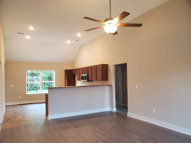 kitchen featuring stainless steel microwave, baseboards, and wood finished floors