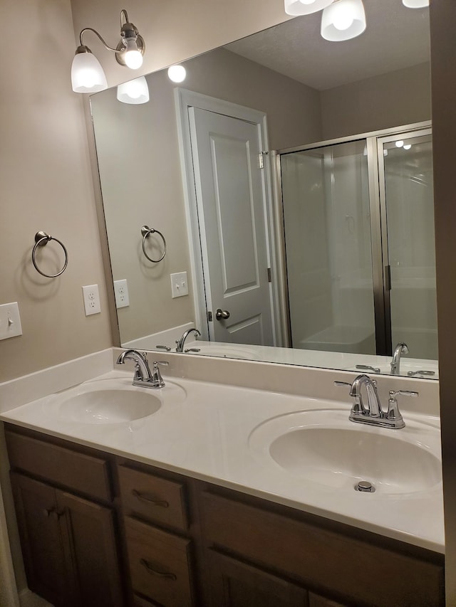 full bath with a shower stall, double vanity, and a sink