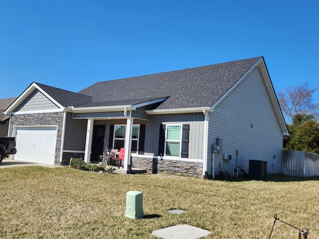 view of front of house with board and batten siding, a front yard, an attached garage, and stone siding