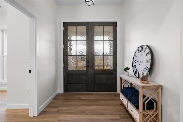 doorway to outside with french doors, baseboards, and light wood-style floors