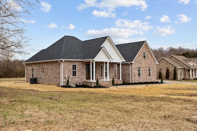 view of front of house featuring a front yard, brick siding, and roof with shingles