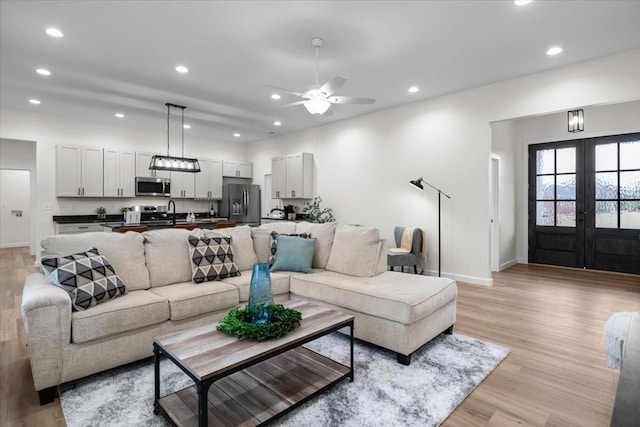 living area with baseboards, light wood finished floors, recessed lighting, ceiling fan, and french doors