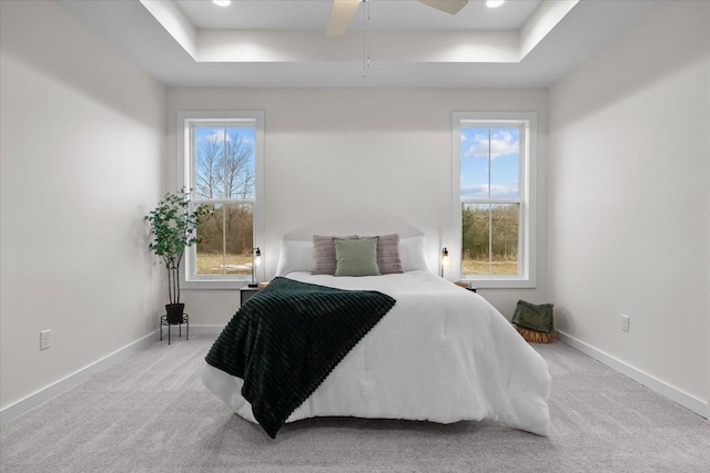 carpeted bedroom with recessed lighting, baseboards, a tray ceiling, and a ceiling fan