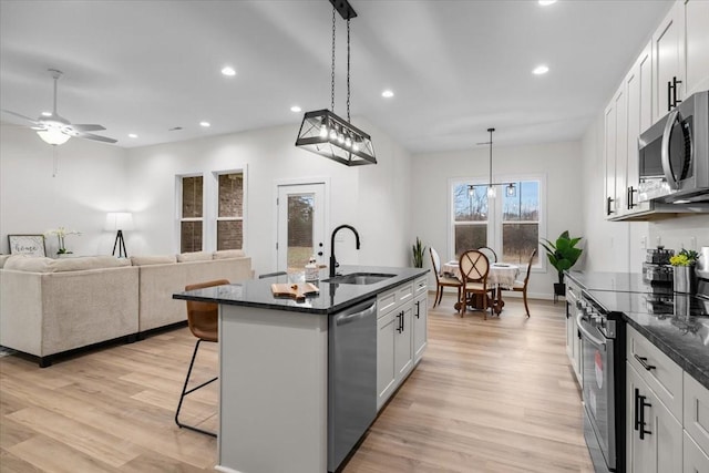 kitchen with a sink, light wood-type flooring, a kitchen bar, and stainless steel appliances