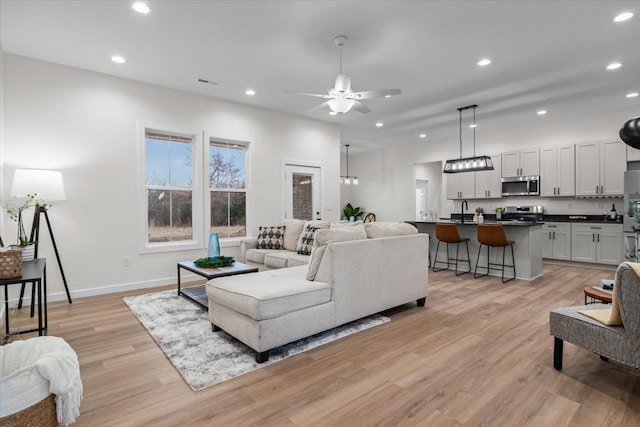 living room featuring visible vents, baseboards, recessed lighting, ceiling fan, and light wood-style floors