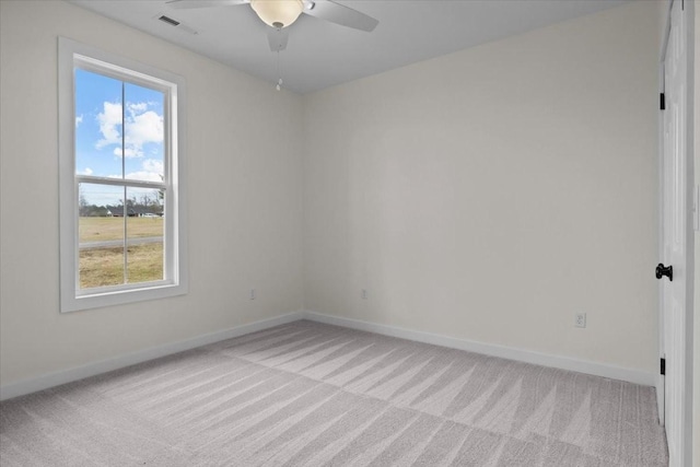 empty room with a ceiling fan, light colored carpet, visible vents, and baseboards