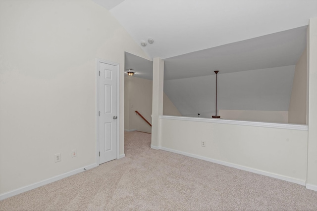 carpeted spare room with lofted ceiling and baseboards