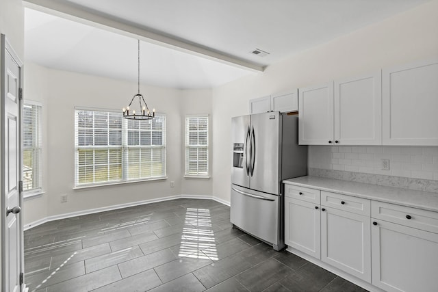 kitchen with visible vents, a notable chandelier, pendant lighting, stainless steel refrigerator with ice dispenser, and decorative backsplash