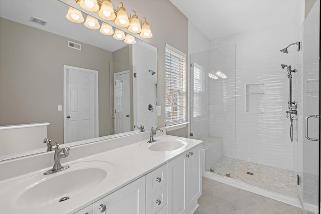 full bathroom featuring double vanity, a stall shower, visible vents, and a sink