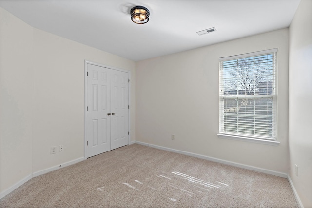 carpeted spare room with visible vents and baseboards