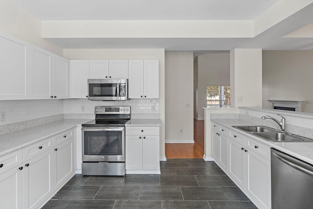 kitchen with a sink, tasteful backsplash, white cabinetry, and stainless steel appliances