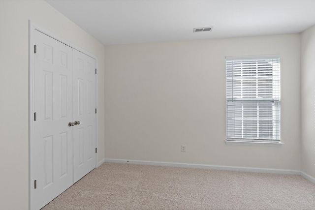 unfurnished bedroom featuring baseboards, visible vents, carpet floors, and a closet