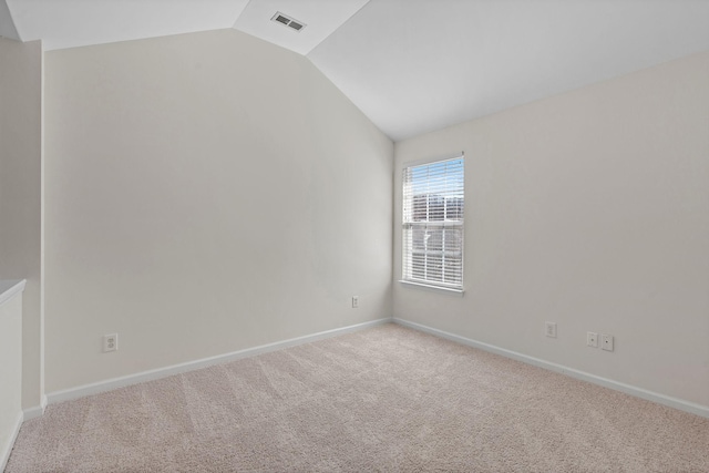 unfurnished room with vaulted ceiling, carpet flooring, baseboards, and visible vents