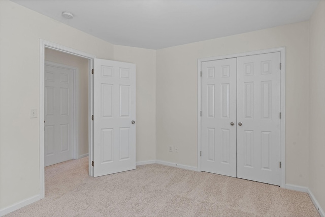 unfurnished bedroom with a closet, carpet flooring, and baseboards