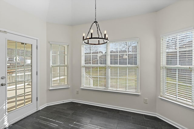 unfurnished dining area with an inviting chandelier, a healthy amount of sunlight, and baseboards