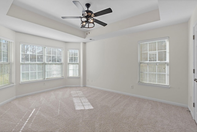 empty room with a raised ceiling, baseboards, and carpet floors