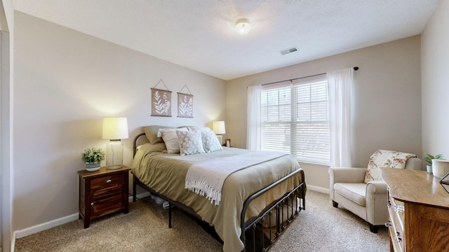 bedroom featuring visible vents, light colored carpet, a textured ceiling, and baseboards