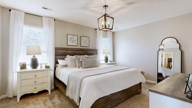 bedroom featuring a notable chandelier, baseboards, visible vents, and light carpet