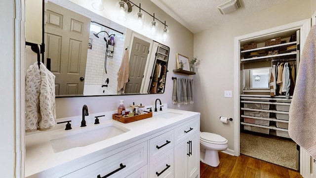 bathroom featuring wood finished floors, a textured ceiling, toilet, and a sink