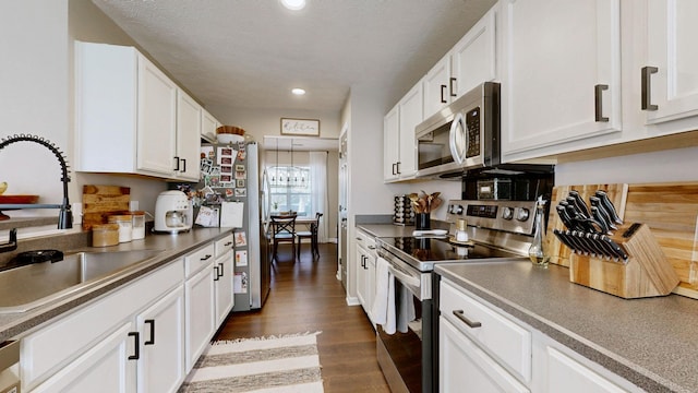 kitchen featuring stainless steel appliances, dark wood-style floors, a textured ceiling, white cabinetry, and a sink