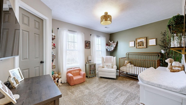 carpeted bedroom with a textured ceiling and a nursery area