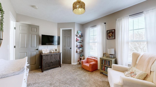 sitting room with a textured ceiling, baseboards, and light carpet