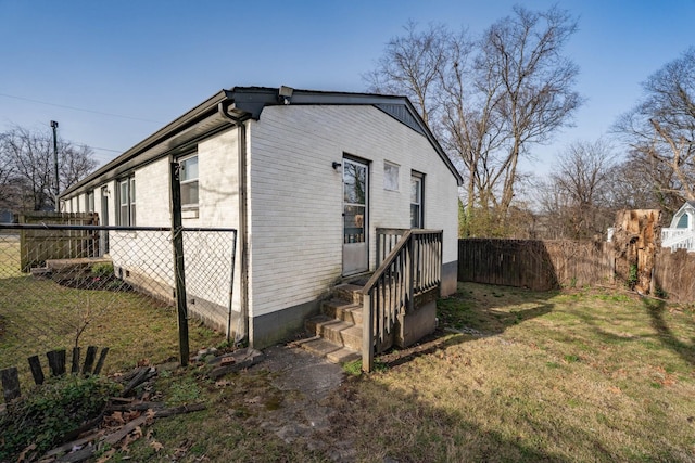 view of side of property featuring crawl space, a yard, brick siding, and fence