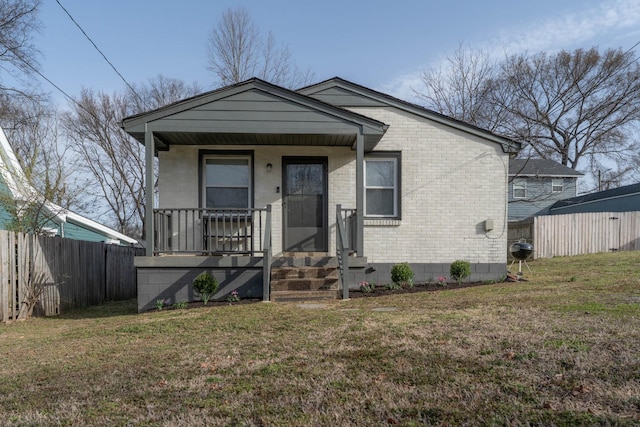 bungalow-style house with brick siding, covered porch, a front lawn, and fence