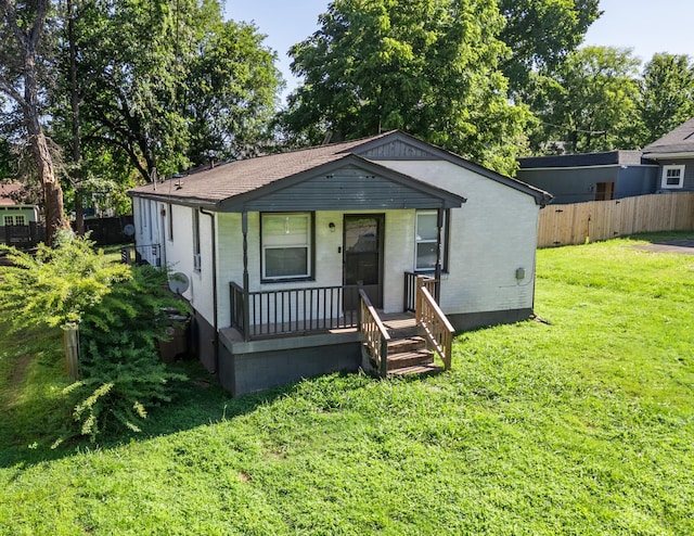 bungalow-style house with brick siding, a front lawn, fence, and covered porch