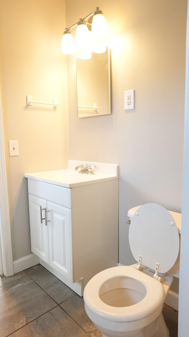 bathroom featuring toilet, vanity, and baseboards