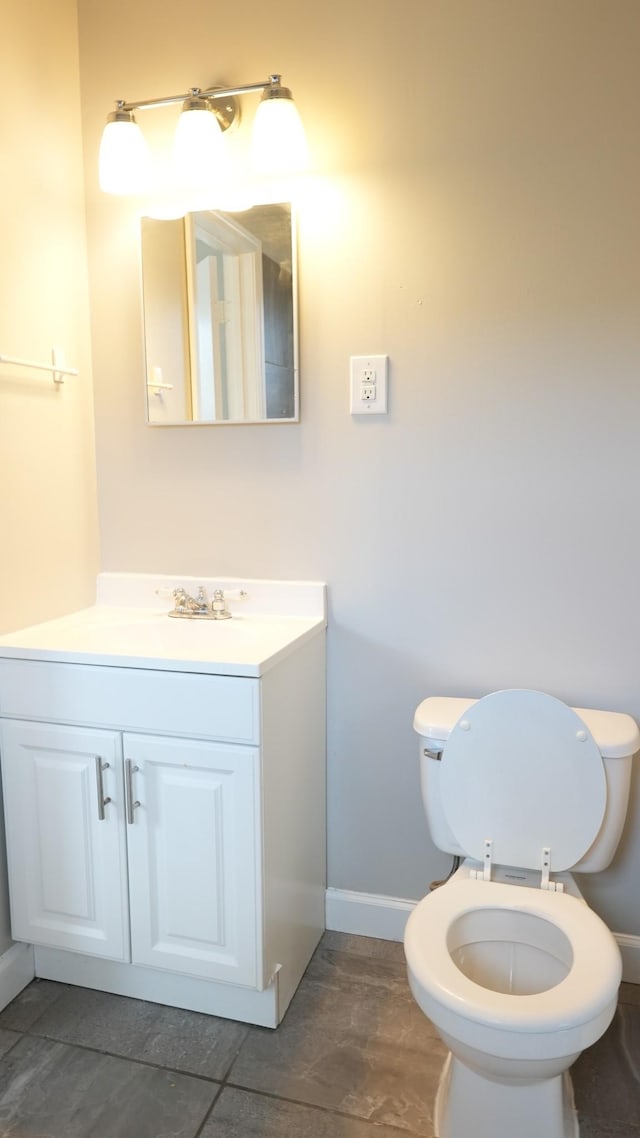 half bathroom with baseboards, toilet, and vanity