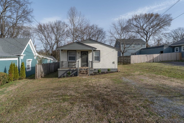 bungalow-style home with brick siding, a front lawn, and fence