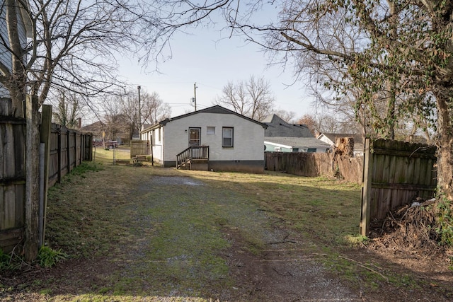 back of property with stucco siding, a lawn, and a fenced backyard