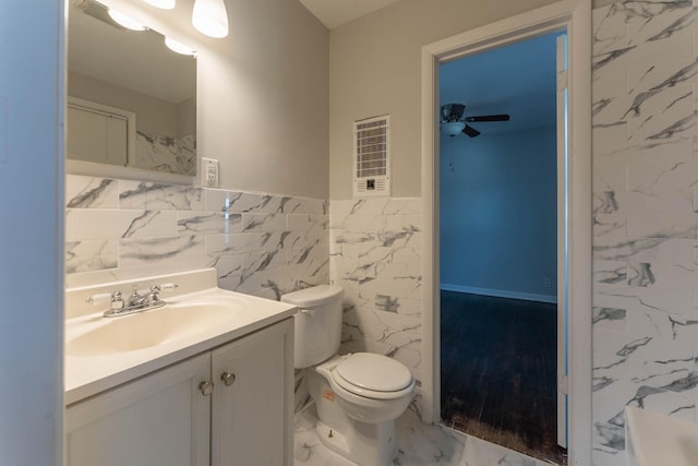 full bathroom featuring ceiling fan, toilet, vanity, marble finish floor, and tile walls