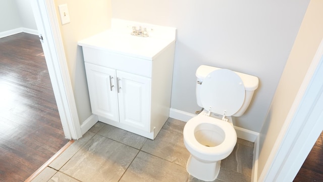 bathroom with baseboards, toilet, and vanity