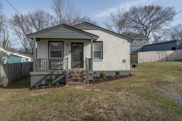 bungalow with a front yard, fence, brick siding, and covered porch