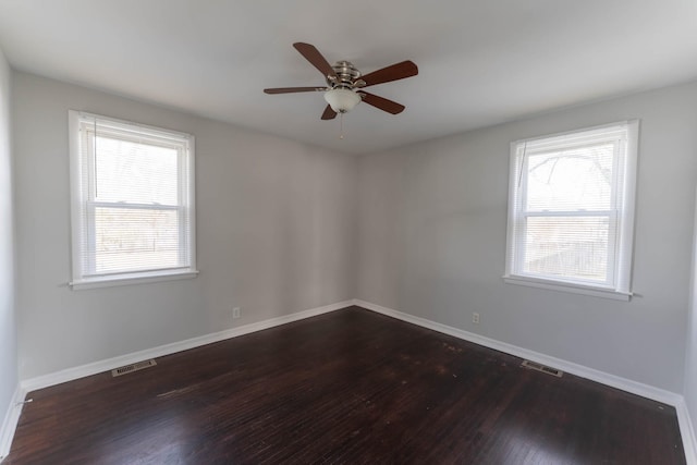 empty room featuring a ceiling fan, dark wood-type flooring, visible vents, and baseboards