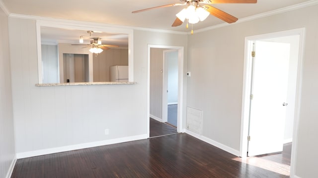 spare room with visible vents, crown molding, ceiling fan, baseboards, and wood finished floors