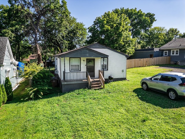 view of front of property with covered porch, a front lawn, and fence