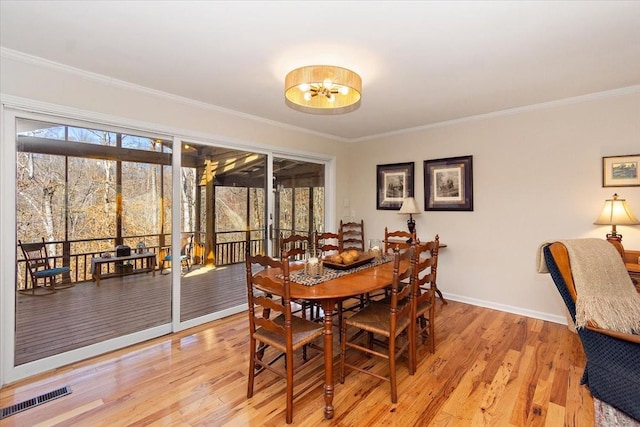 dining room with visible vents, ornamental molding, and light wood-style floors